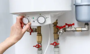 Mano ajustando el control de temperatura de una caldera, mostrando cómo funciona una caldera para calentar agua.
