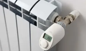 Termostato inteligente en radiador blanco, mostrando 18.0°C. Controla la temperatura en casa para mayor confort.