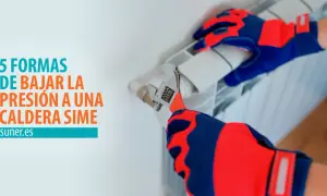 Manos enguantadas ajustan una llave inglesa a un radiador, mostrando cómo quitar presión a la caldera.