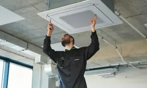 Técnico ajustando un cassette de aire centralizado en el techo.