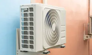 Unidad exterior de aire acondicionado gotea agua. La unidad interior, montada en la pared, muestra su ventilador circular y rejillas de ventilación.