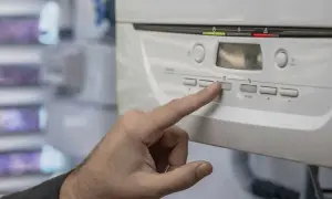 Dedo presionando botón en caldera Saunier Duval para bajar presión.