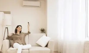 Mujer relajada en sofá con control remoto, pensando cuántas frigorías para 30 metros cuadrados necesita su hogar.