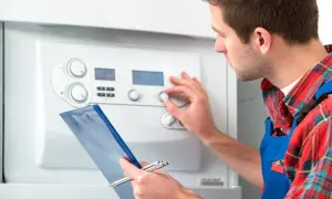 Técnico revisa una caldera bloqueada, ajustando controles y anotando en una carpeta azul.