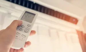 Mano ajustando el control remoto de un aire acondicionado para disfrutar de unas agradables frigorías.