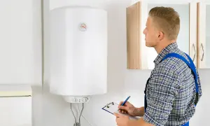 Técnico revisa un termo eléctrico blanco, anotando en una libreta.