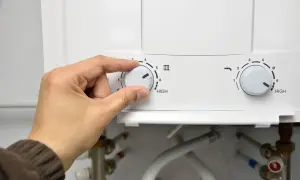 Mano ajustando el dial de temperatura de un termo eléctrico. Se acerca el momento de desmontar el termo eléctrico para su mantenimiento.