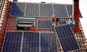 Instalación de placas solares en Extremadura. Dos operarios colocan un panel solar en un tejado, aprovechando la subvención.