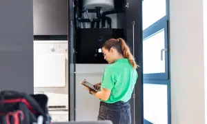 Técnica revisa sistema de aerotermia en armario con tablet.