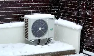 Unidad exterior de bomba de calor Kosner cubierta de nieve, mostrando su capacidad para mantener la temperatura en invierno.