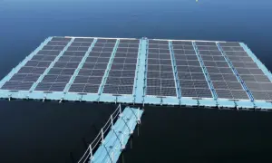 Plataforma de energía fotovoltaica flotante sobre un cuerpo de agua azul, con un pasarela azul conectada.
