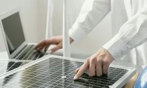Persona revisa placas solares mientras trabaja en una laptop.
