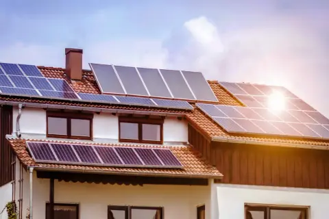 Casa con paneles solares fotovoltaicos en el tejado, captando la luz del sol para generar energía limpia.