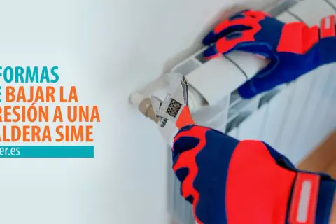 Manos enguantadas ajustan una llave inglesa a un radiador, mostrando cómo quitar presión a la caldera.