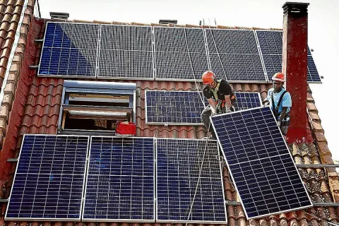 Instalación de placas solares en Extremadura. Dos operarios colocan un panel solar en un tejado, aprovechando la subvención.