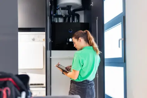 Técnica revisa sistema de aerotermia en armario con tablet.