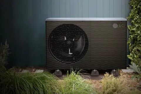 Unidad exterior de bomba de calor LG, una de las alternativas a la aerotermia, instalada en un jardín.