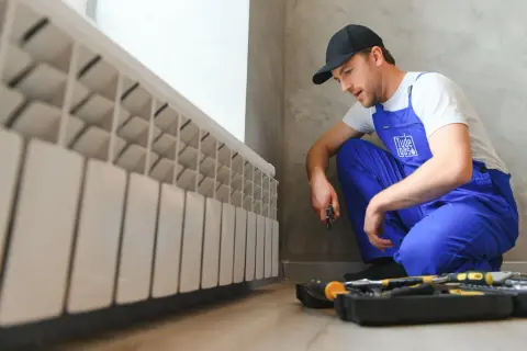 Técnico en azul revisa radiador. Preparado para cambiar caldera de gas.
