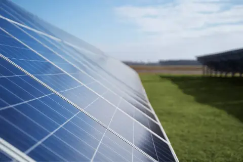 Paneles solares en un campo verde. ¿Cuántos kWh produce un panel solar de 450W? La energía solar es el futuro.