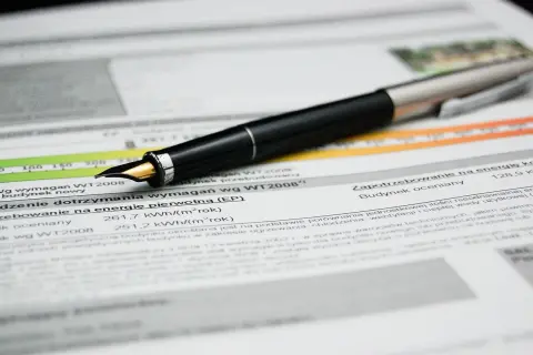 Pluma sobre documento con datos de certificado eficiencia energética Euskadi. Muestra consumo y requisitos.