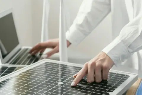 Persona revisa placas solares mientras trabaja en una laptop.