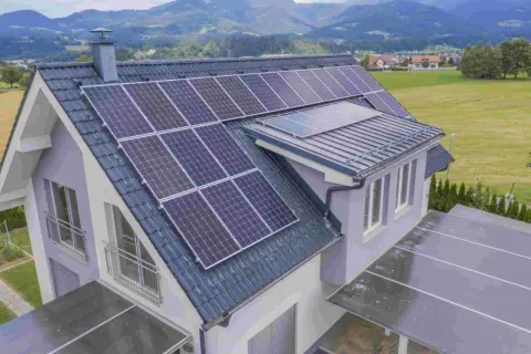 Tejado de casa de campo con paneles solares y vistas a montañas verdes.