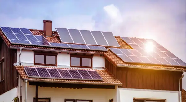 Casa con paneles solares fotovoltaicos en el tejado, captando la luz del sol para generar energía limpia.