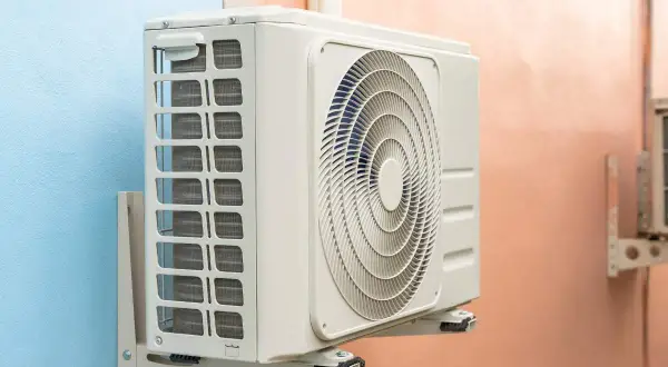 Unidad exterior de aire acondicionado gotea agua. La unidad interior, montada en la pared, muestra su ventilador circular y rejillas de ventilación.
