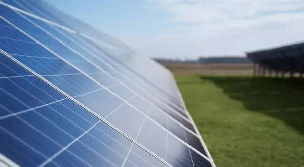 Paneles solares en un campo verde. ¿Cuántos kWh produce un panel solar de 450W? La energía solar es el futuro.