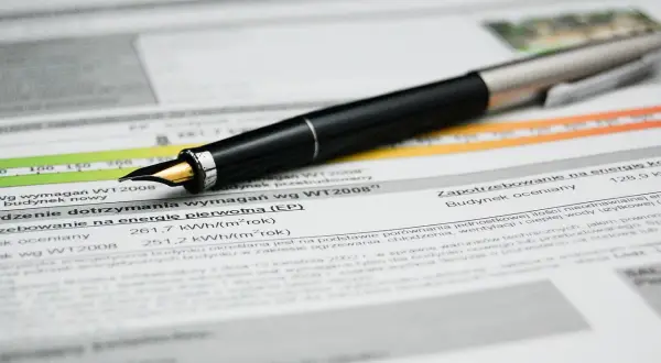 Pluma sobre documento con datos de certificado eficiencia energética Euskadi. Muestra consumo y requisitos.