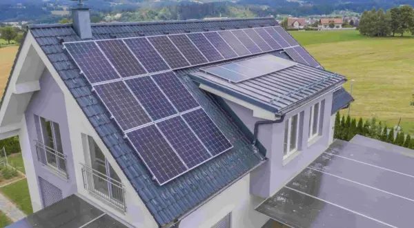 Tejado de casa de campo con paneles solares y vistas a montañas verdes.