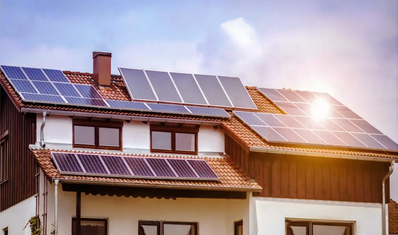 Casa con paneles solares fotovoltaicos en el tejado, captando la luz del sol para generar energía limpia.