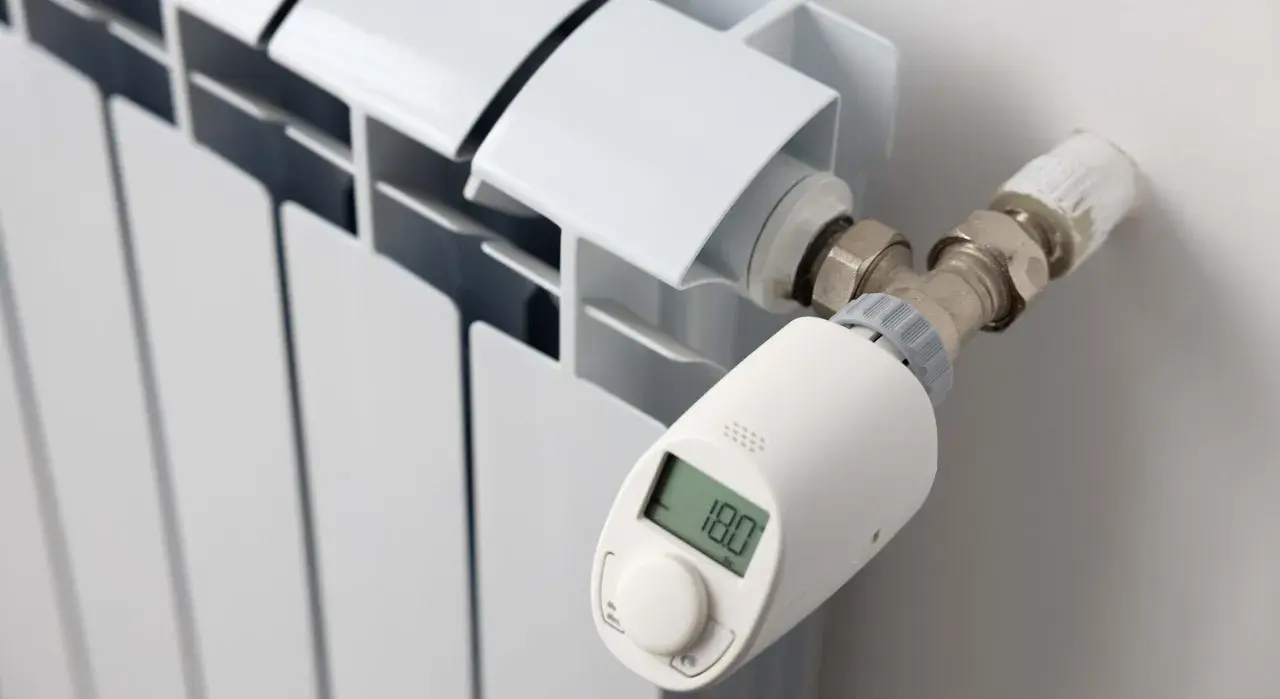 Termostato inteligente en radiador blanco, mostrando 18.0°C. Controla la temperatura en casa para mayor confort.