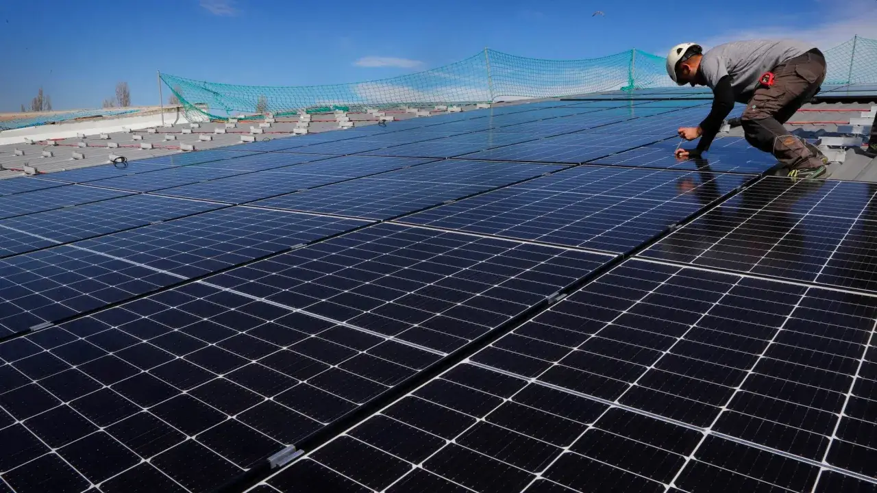Instalaci&oacute;n de paneles solares para autoconsumo en la Comunidad Valenciana. Un trabajador ajusta un panel bajo un cielo azul.