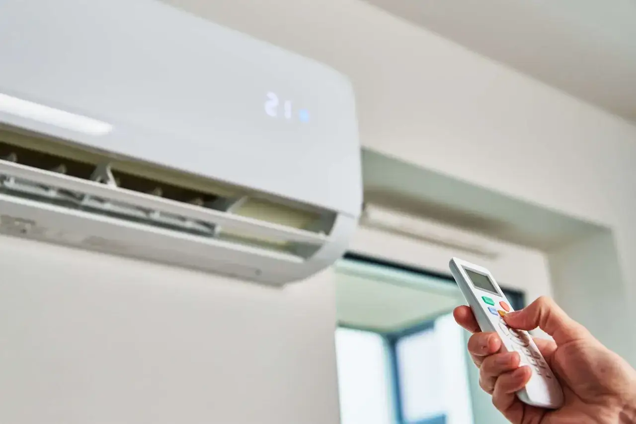 Mano operando un control remoto para un cool aire acondicionado, ajustando la temperatura a 21 grados.