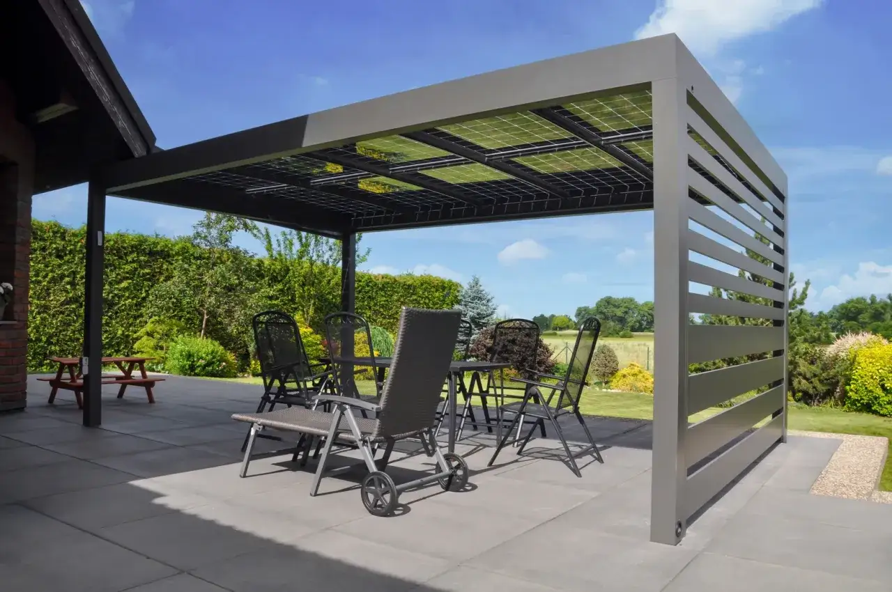 Moderna pérgola fotovoltaica en terraza con mesa y sillas, ideal para disfrutar del exterior y generar energía.