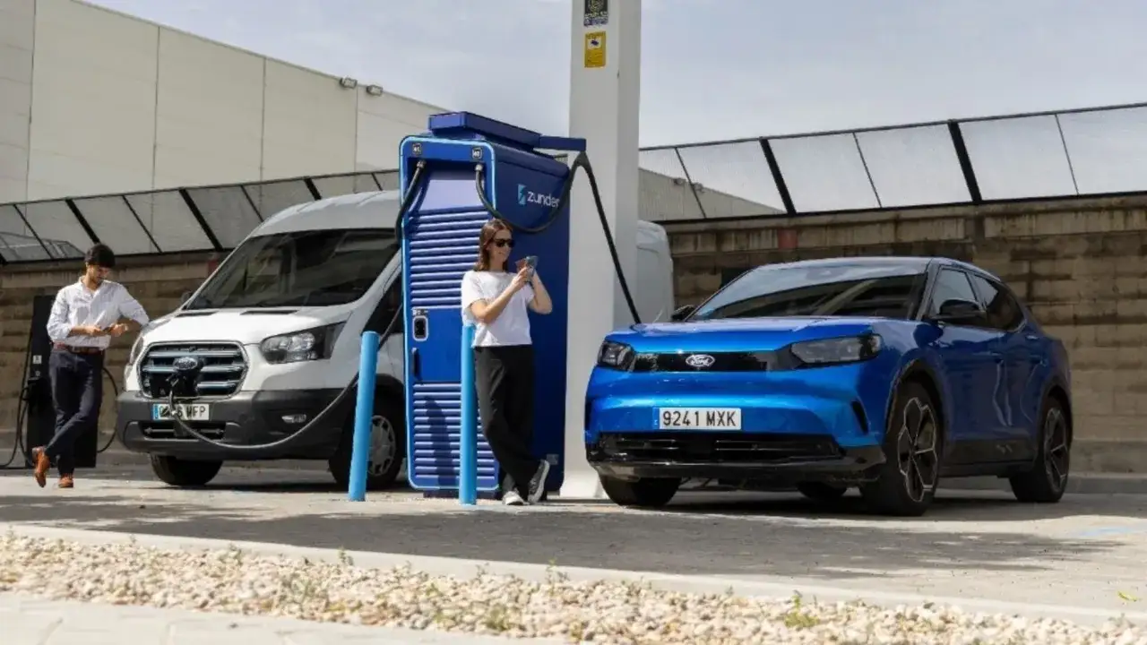 Un hombre y una mujer cargan sus coches el&eacute;ctricos. La deducci&oacute;n del IRPF por coche el&eacute;ctrico es una ventaja fiscal.