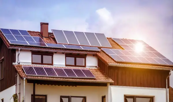 Casa con paneles solares fotovoltaicos en el tejado, captando la luz del sol para generar energía limpia.