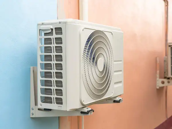 Unidad exterior de aire acondicionado gotea agua. La unidad interior, montada en la pared, muestra su ventilador circular y rejillas de ventilación.