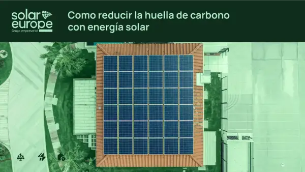 Vista aérea de un tejado con un gran conjunto de placas solares. El texto indica "Cómo reducir la huella de carbono con energía solar".