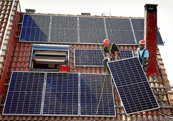 Instalación de placas solares en Extremadura. Dos operarios colocan un panel solar en un tejado, aprovechando la subvención.