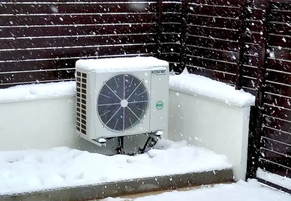 Unidad exterior de bomba de calor Kosner cubierta de nieve, mostrando su capacidad para mantener la temperatura en invierno.
