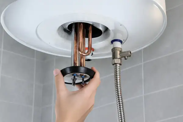Mano retirando resistencia de termo eléctrico. ¿Cuánto tarda en vaciarse un termo eléctrico de 80 litros?