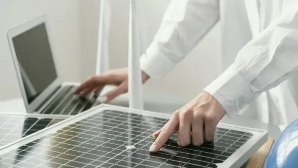 Persona revisa placas solares mientras trabaja en una laptop.